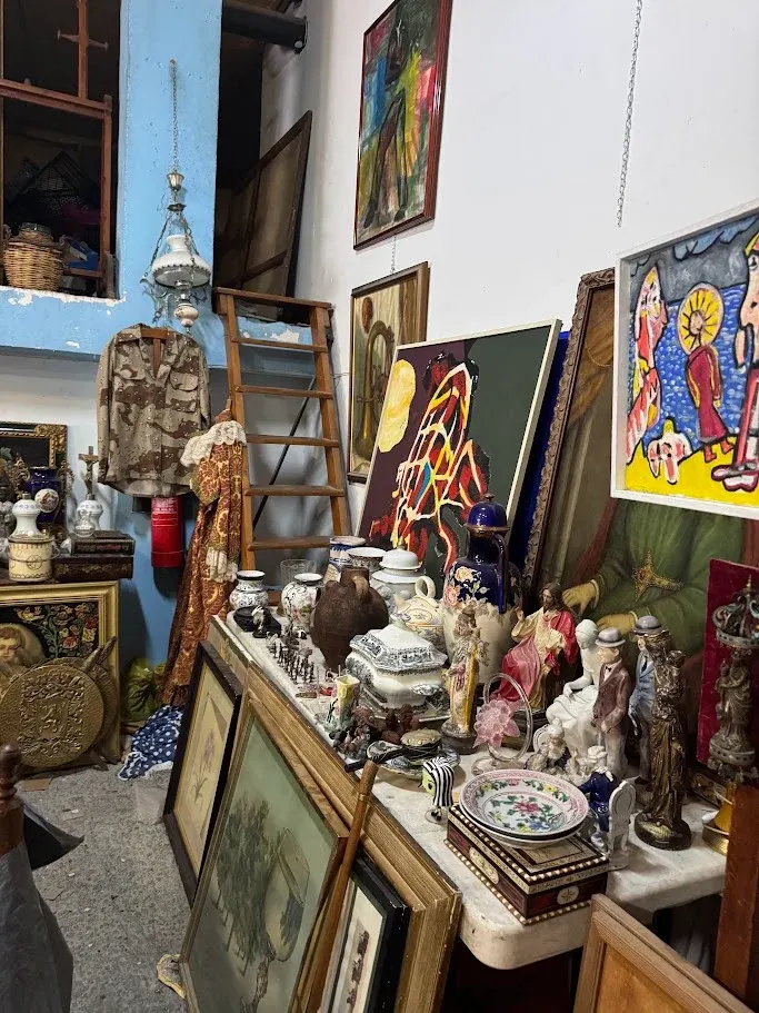 Cuadros, loza, jarrones y figuras religiosas sobre una mesa de mármol en la tienda