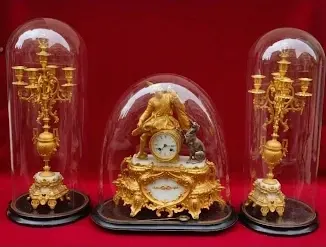 Reloj de sobremesa antiguo dorado con candelabros bajo fanal, antigüedad valorada por fotos