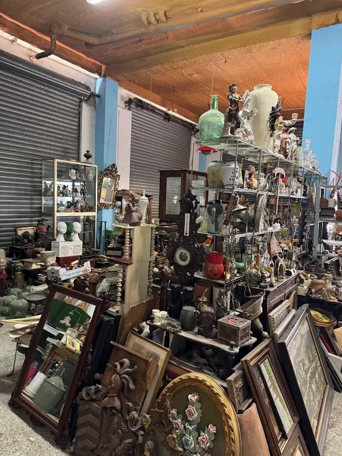 Estanterías con jarrones, figuras, reloj de pared y espejos antiguos
